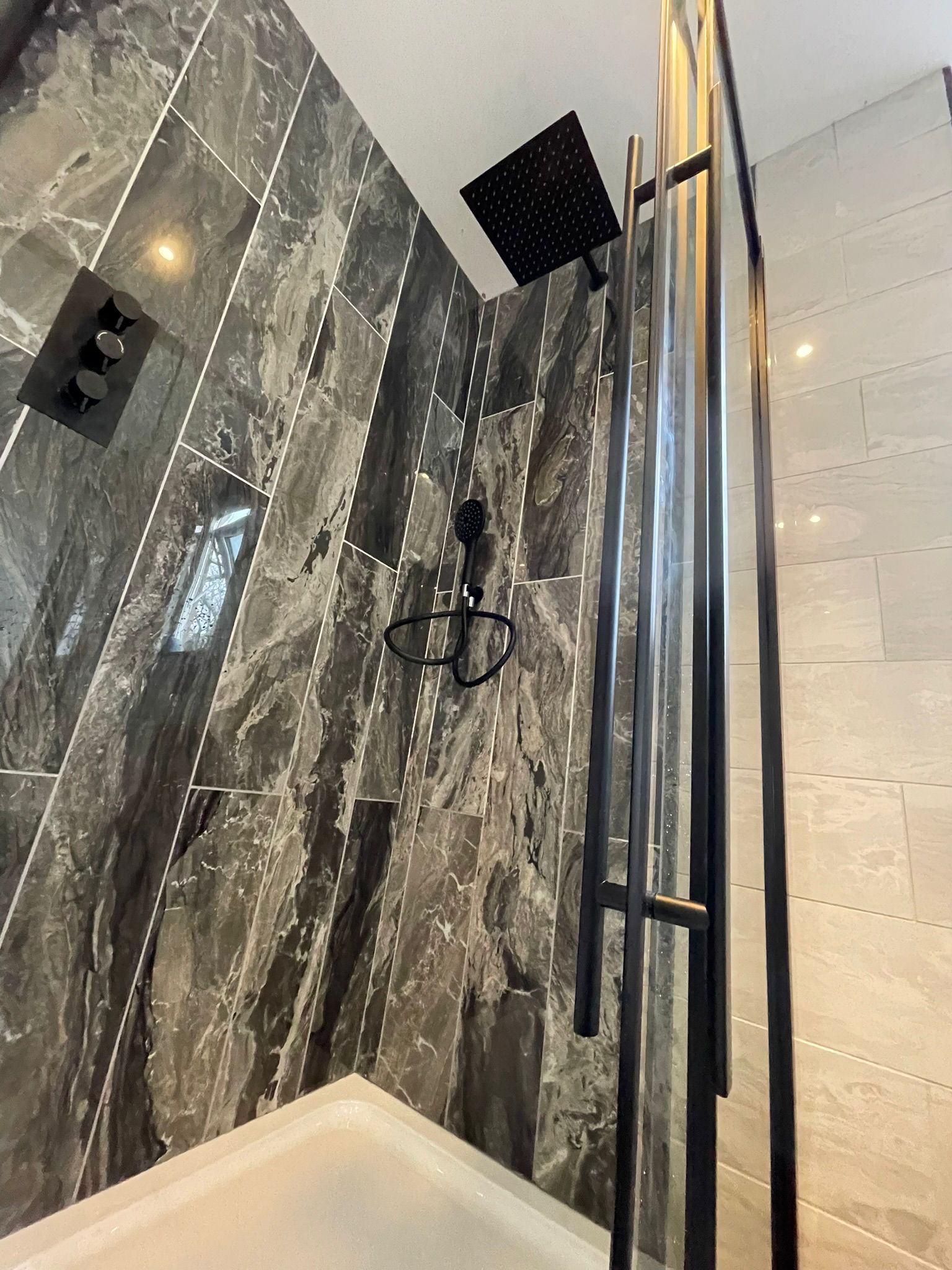 Black rainfall shower with marble wall tiles