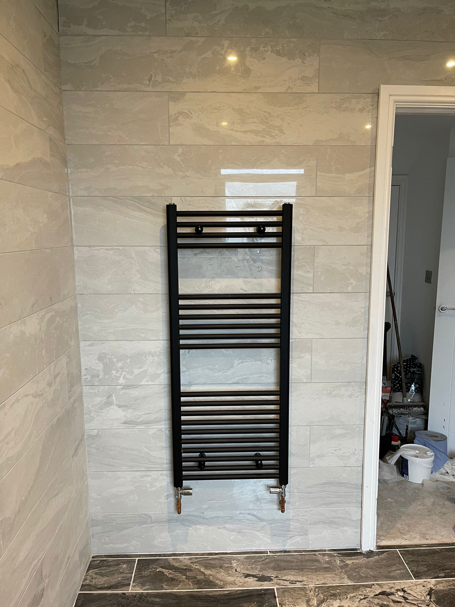 Black towel radiator on marble tiles