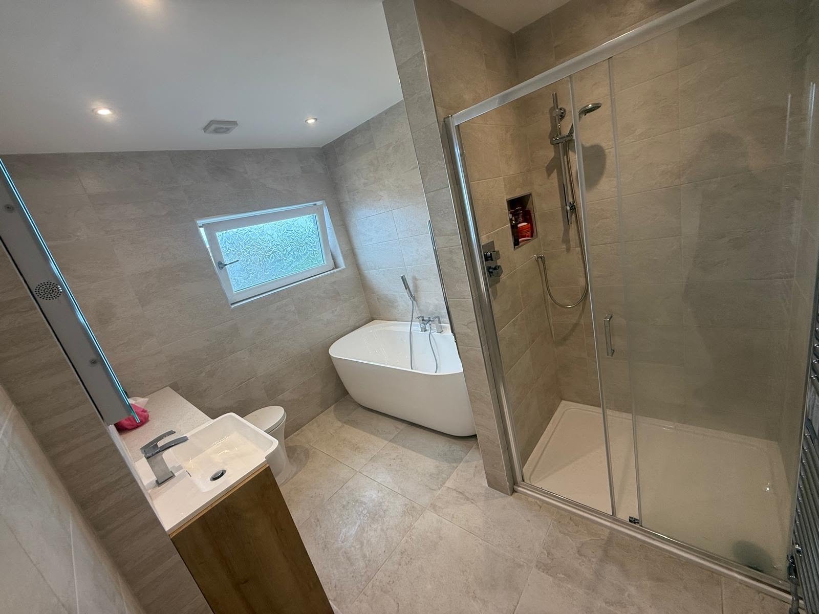 Sandstone tiled bathroom with freestanding bath and shower