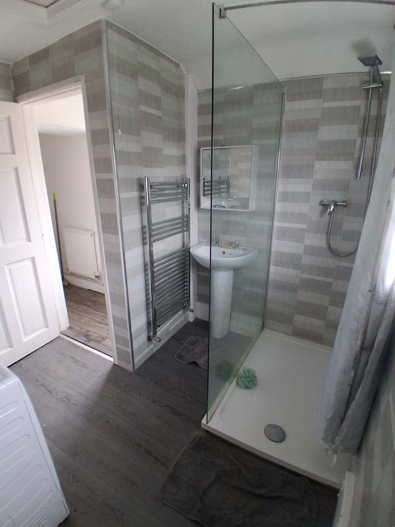 Shower room with glass enclosure and chrome towel rail